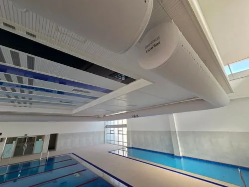 Fabric ductwork running the length of a sports hall ceiling above a pool